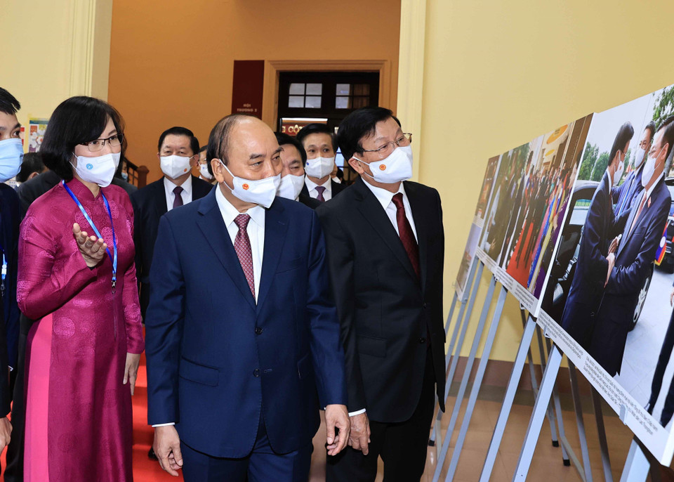 Phó Tổng Giám đốc Thông tấn xã Việt Nam Vũ Việt Trang giới thiệu trưng bày ảnh của TTXVN với Tổng Bí thư, Chủ tịch nước Lào Thongloun Sisoulith và Chủ tịch nước Nguyễn Xuân Phúc. (Ảnh: Thống Nhất/TTXVN)