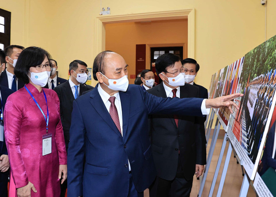 Phó Tổng Giám đốc Thông tấn xã Việt Nam Vũ Việt Trang giới thiệu trưng bày ảnh của TTXVN với Tổng Bí thư, Chủ tịch nước Lào Thongloun Sisoulith và Chủ tịch nước Nguyễn Xuân Phúc. (Ảnh: Thống Nhất/TTXVN)