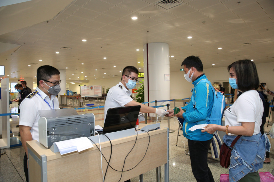 Nhân viên y tế kiểm tra phiếu khai báo y tế của hành khách trước khi làm thủ tục nhập cảnh tại cửa khẩu Sân bay quốc tế Nội Bài (Hà Nội), chiều 7/3. (Ảnh: Dương Giang/TTXVN)