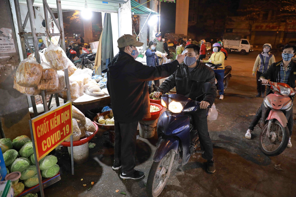 Ban Quản lý chợ tổ chức đo thân nhiệt cho 100% người ra vào chợ. (Ảnh: Vũ SInh/TTXVN)