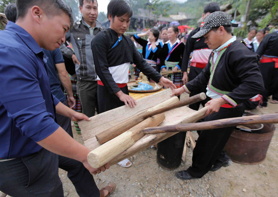 Sau khi chõ xôi bốc hơi các thành viên khiêng cối ra chuẩn bị cho hội thi giã bánh giầy. (Ảnh: Quý Trung/TTXVN)