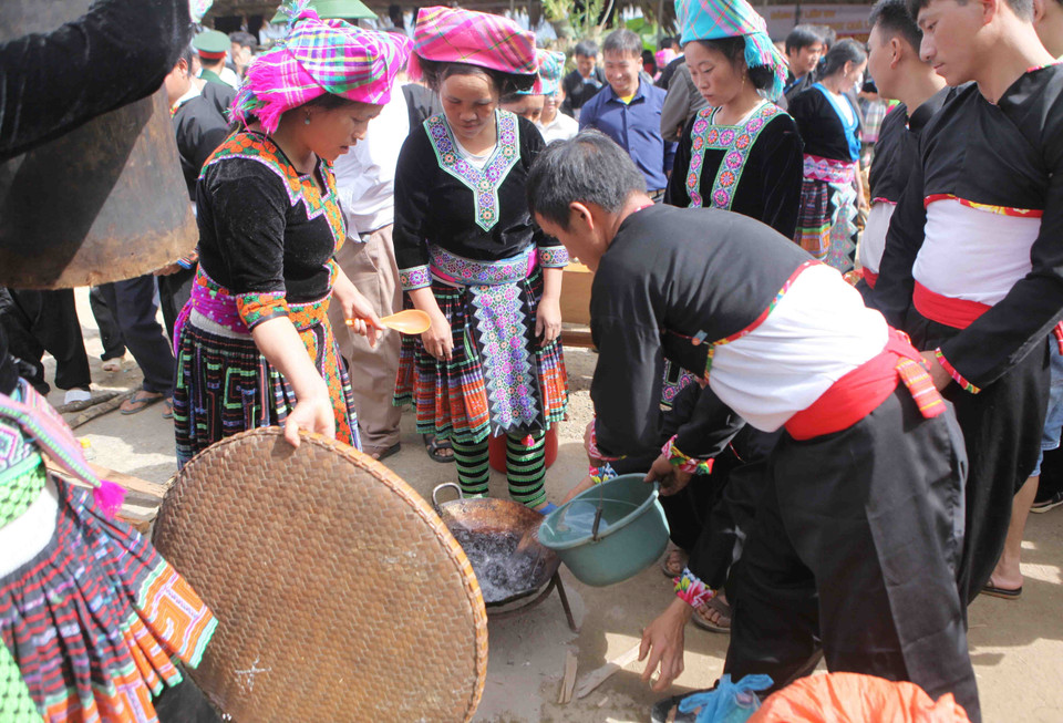 Cho nước vào chảo để nấu sao cho khi gạo chín mà không bị cạn và không quá nhiều để không mất nhiều thời gian đồ xôi. (Ảnh: Quý Trung/TTXVN)
