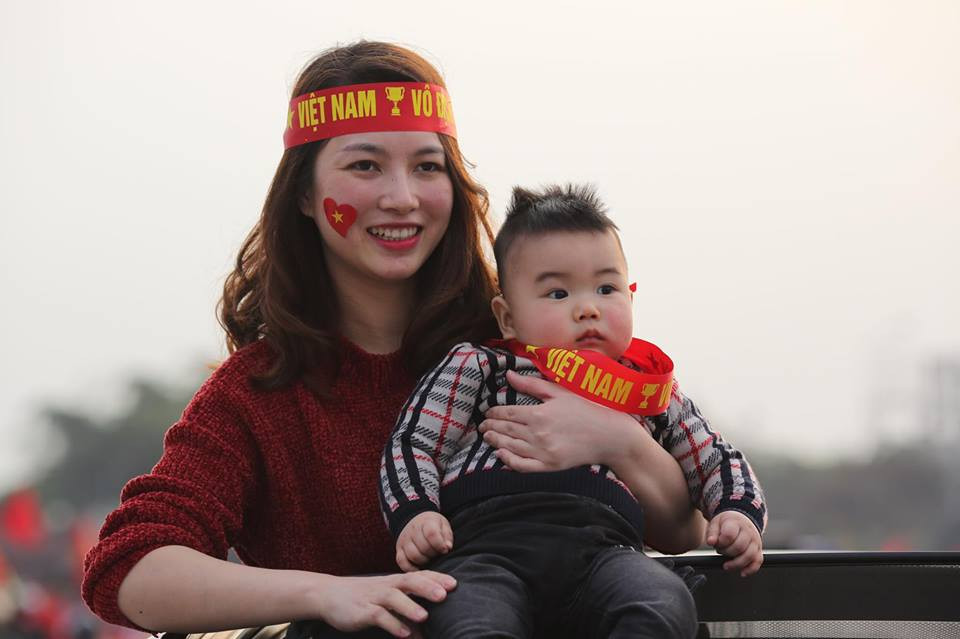 Một phụ nữ trẻ cũng ôm theo đứa bé đi cổ động cho đội tuyển Việt Nam. (Ảnh: Minh Sơn/Vietnam+)