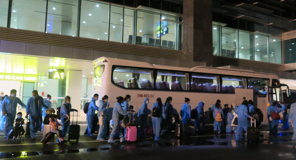 Công dân Việt Nam về nước lên các xe trung chuyển đến điểm cách ly tập trung 14 ngày do quân đội quản lý. (Ảnh: Phan Sáu/TTXVN)