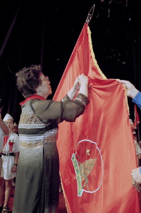 Phó Chủ tịch nước Nguyễn Thị Bình gắn Huân chương Sao vàng lên lá cờ truyền thống của Đội Thiếu niên Tiền phong Hồ Chí Minh (2001). (Ảnh: Đình Trân/TTXVN)