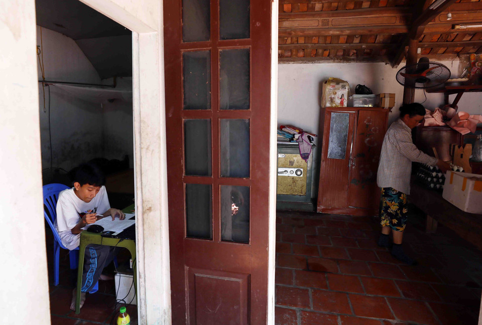 Cùng với ý chí vươn lên, chàng trai nhỏ bé không ngừng nỗ lực học tập để thắp sáng ước mơ trong ngôi nhà nhỏ của 2 mẹ con. (Ảnh: Phạm Kiên/TTXVN)