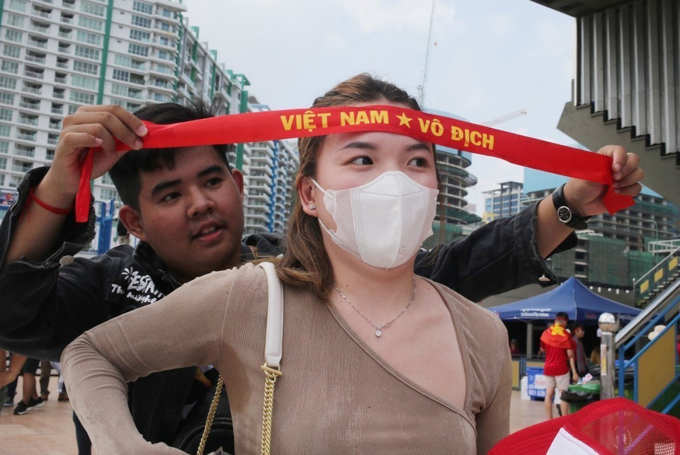 Các cổ động viên Việt Nam đều không quên đeo chiếc băng rôn quen thuộc trên trán trước khi vào sân cổ vũ cho đội nhà. (Ảnh: Hoàng Linh/TTXVN)
