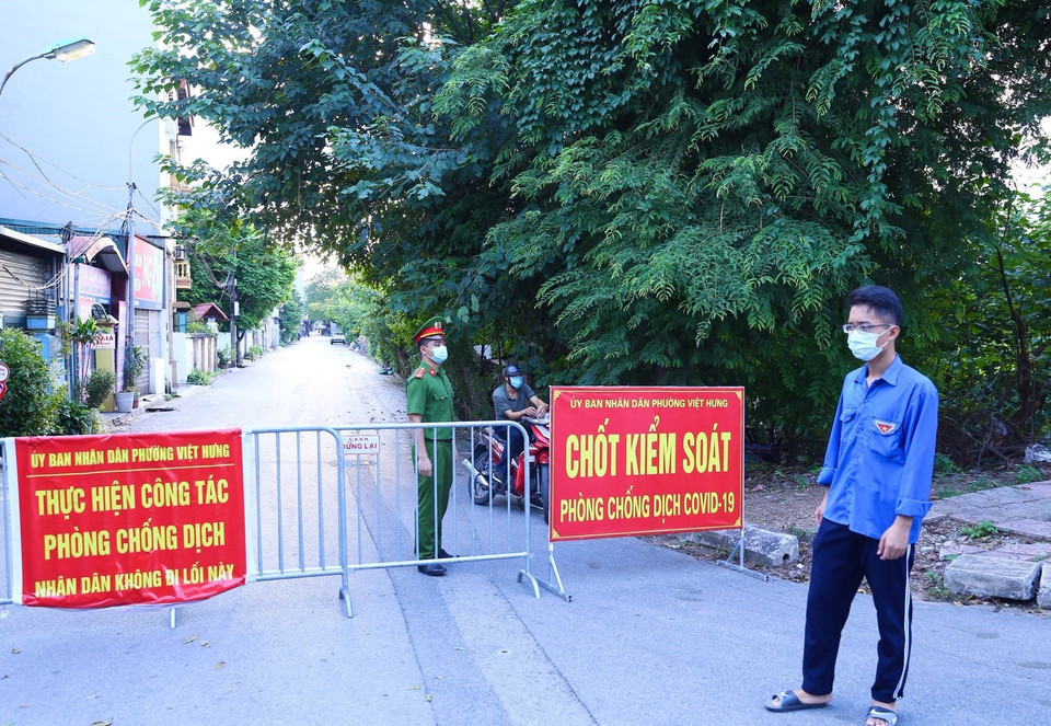 Lực lượng chức năng phường Việt Hưng chốt chặn các ngả đường để thực hiện nghiêm việc cách ly tạm thời. (Ảnh: Hoàng Hiếu/TTXVN)