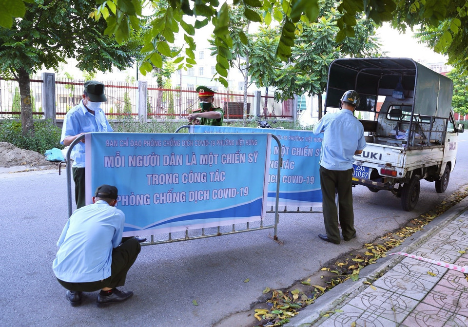 Lực lượng chức năng phường Việt Hưng (Long Biên) chuẩn bị rào chắn để phong tỏa khu vực. (Ảnh: Hoàng Hiếu/TTXVN)