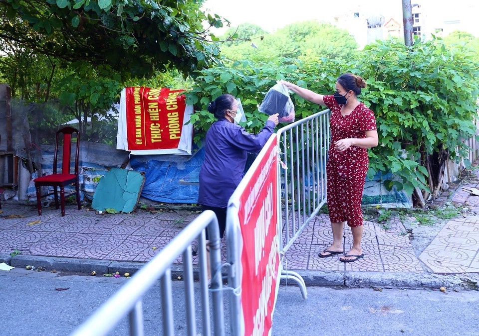Người dân khu vực phong tỏa phường Việt Hưng nhận đồ tiếp tế từ bên ngoài chiều 18/9. (Ảnh: Hoàng Hiếu/TTXVN)