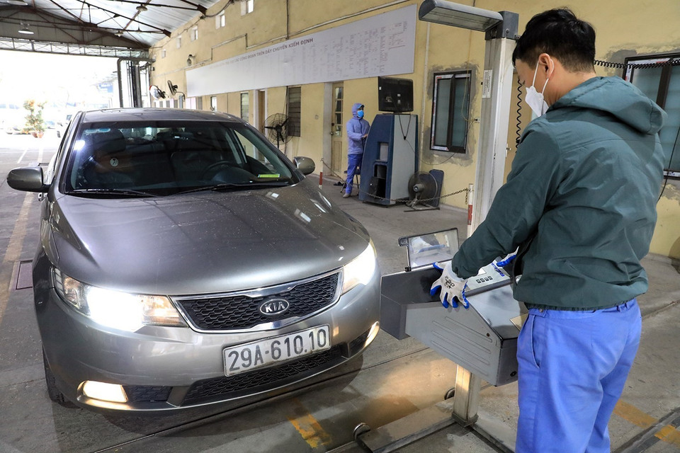 Cán bộ Trung tâm đăng kiểm xe cơ giới số 29.03V kiểm tra độ chiếu sáng của phương tiện. (Ảnh: Tuấn Anh/TTXVN)