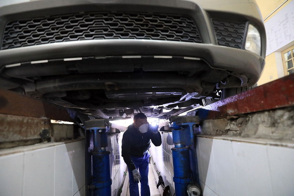 Cán bộ kỹ thuật kiểm tra khung, gầm bệ của phương tiện vào đăng kiểm tại Trung tâm đăng kiểm xe cơ giới số 29.03V. (Ảnh: Tuấn Anh/TTXVN)