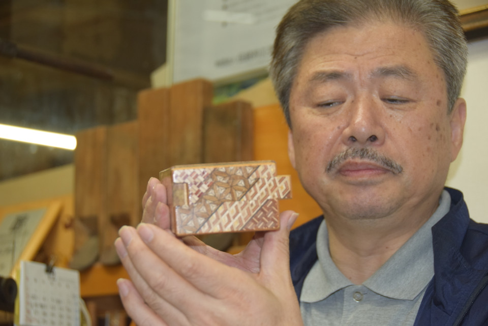 Nghệ nhân đang giới thiệu nguyên tắc hoạt động của một hộp bí ẩn được trang trí bằng hoa văn Yosegi-Zaiku