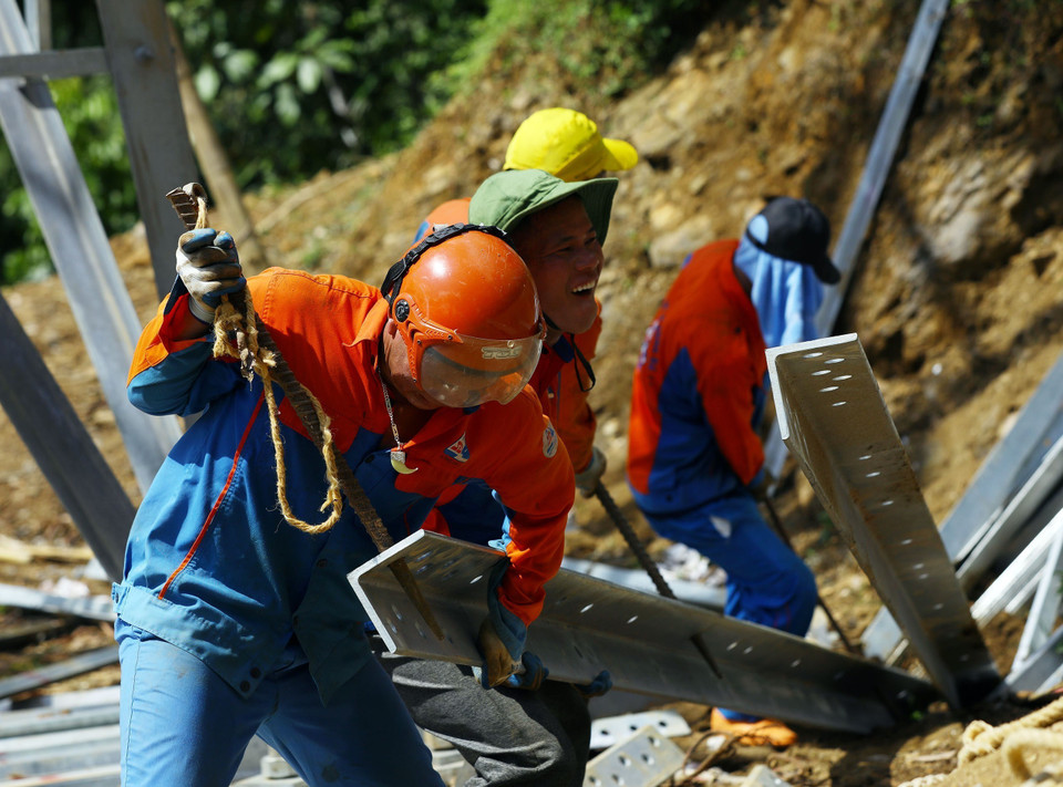 Hàng chục công nhân đang nỗ lực xây lắp từng vị trí cột đã được bàn giao mặt bằng, đảm bảo có thể kéo dây ngay khi công tác đền bù hành lang tuyến hoàn thành. (Ảnh: Huy Hùng/TTXVN)