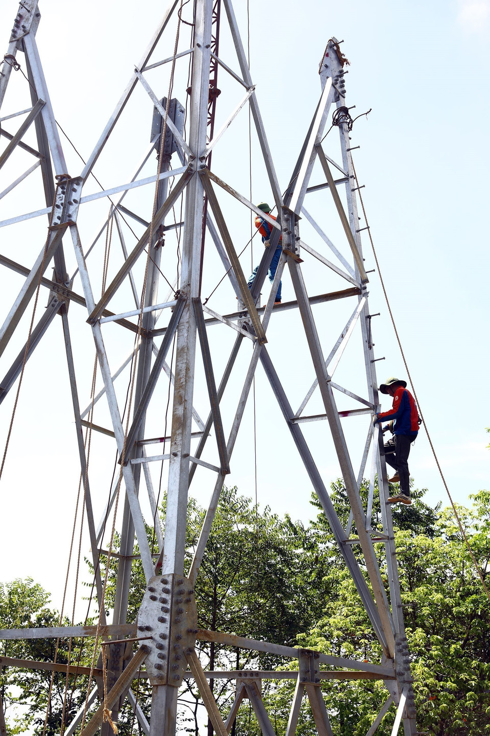 Trong những ngày nắng nóng, những người thợ làm việc trên cột khoảng 1 giờ đồng hồ rồi xuống nghỉ để thay ca. (Ảnh: Huy Hùng/TTXVN)