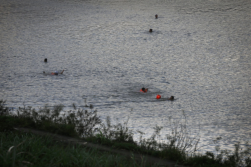 Người lớn lẫn trẻ em xuống tắm sông Đà trong những ngày này khi nước sông đang lên và dòng chảy mạnh, phớt lờ những biển cấm, cảnh báo nguy hiểm. (Ảnh: Trọng Đạt/TTXVN)
