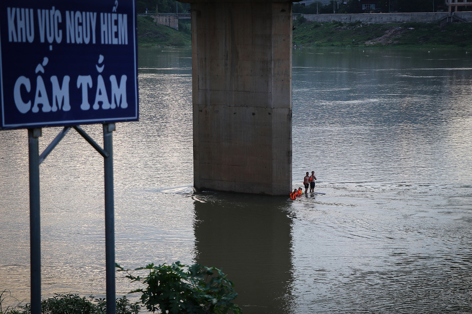 Người lớn lẫn trẻ em xuống tắm sông Đà trong những ngày này khi nước sông đang lên và dòng chảy mạnh, phớt lờ những biển cấm, cảnh báo nguy hiểm. (Ảnh: Trọng Đạt/TTXVN)