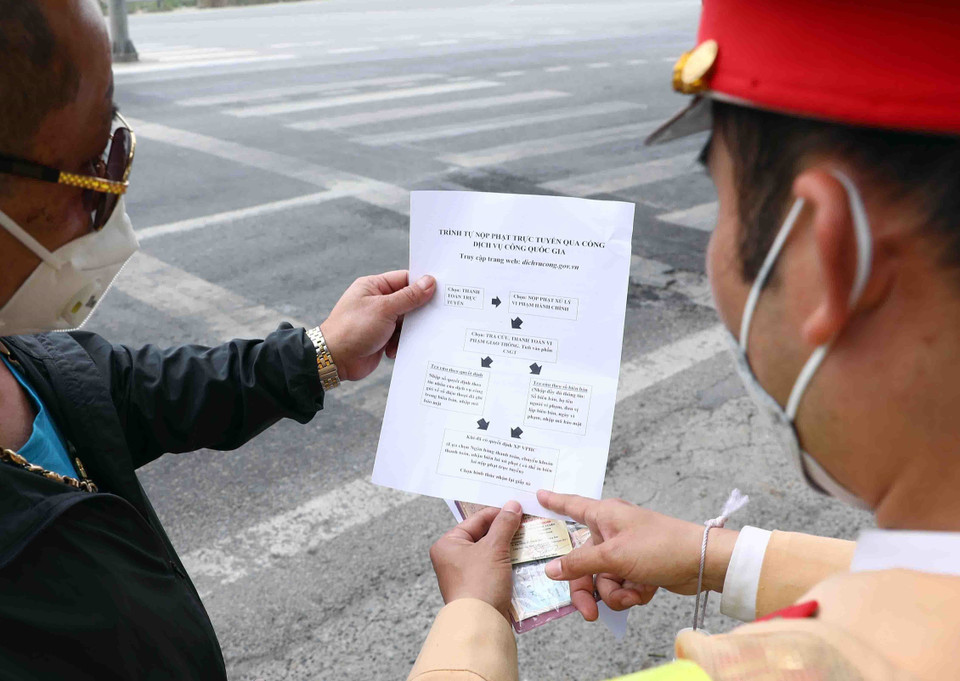 Cán bộ Đội Cảnh sát giao thông số 15 hướng dẫn người vi phạm giao thông nộp phạt trực tuyến qua Cổng dịch vụ công quốc gia. (Ảnh: Phạm Kiên/TTXVN) 