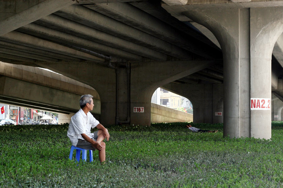 Không ngủ, người đàn ông này đem ghế ra ngồi hóng mát. (Ảnh: Trung Hiền/Vietnam+)