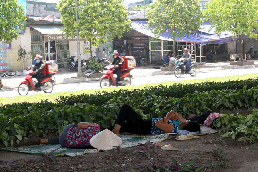 Không chỉ nam giới, cả phụ nữ cũng ra nghỉ trưa dưới gầm đường mát mẻ. Cạnh đó, hai bên đường Nguyễn Xiển vẫn rất nhiều người qua lại, bất chấp cái nắng khủng khiếp của mùa Hè. (Ảnh: Trung Hiền/Vietnam+)