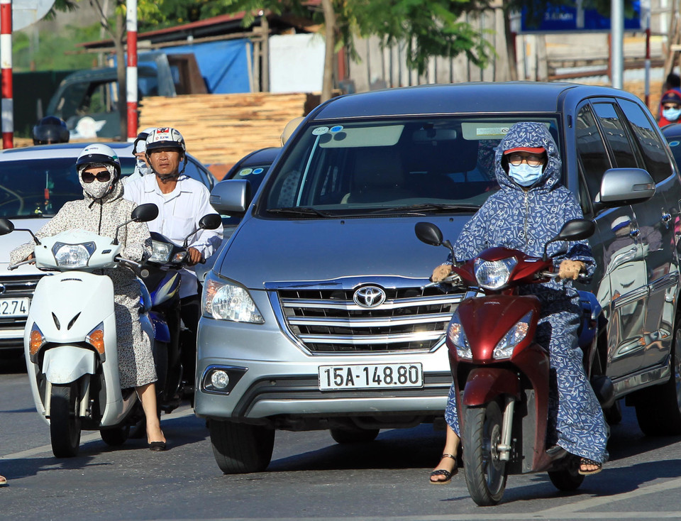  Việc điều khiển xe máy trở nên rất khó khăn khi mặc áo chống nắng quá dài. (Ảnh: An Đăng/TTXVN)