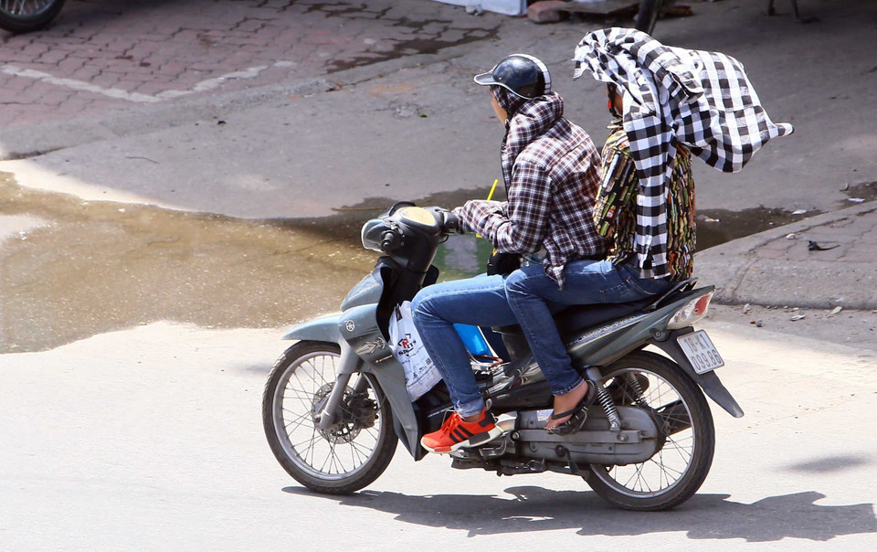 Mỗi khi có việc phải di chuyển ngoài đường người dân đều trang bị cho mình các loại trang phục chống nắng nóng hữu ích nhất có thể. (Ảnh: Quang Quyết/TTXVN)