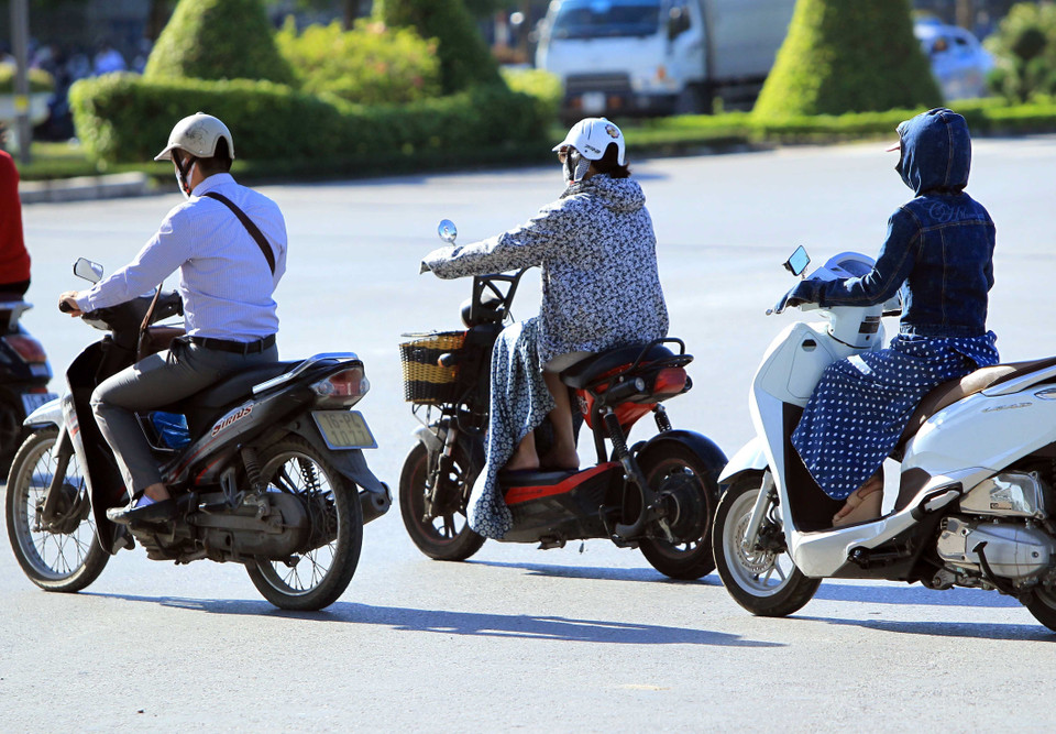 Điều khiển phương tiện giao thông rất khó khăn khi mặc áo chống nắng quá dài. (Ảnh: An Đăng/TTXVN)