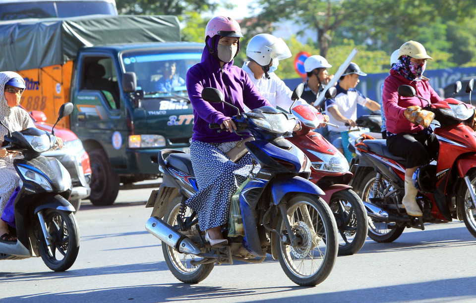Việc điều khiển xe máy trở nên rất khó khăn khi mặc áo chống nắng quá dài. (Ảnh: An Đăng/TTXVN)