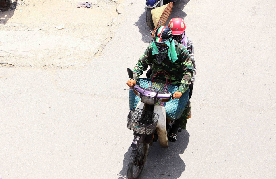 Người dân trang bị cho mình các loại trang phục chống nắng nóng hữu ích nhất có thể. (Ảnh: Quang Quyết/TTXVN)