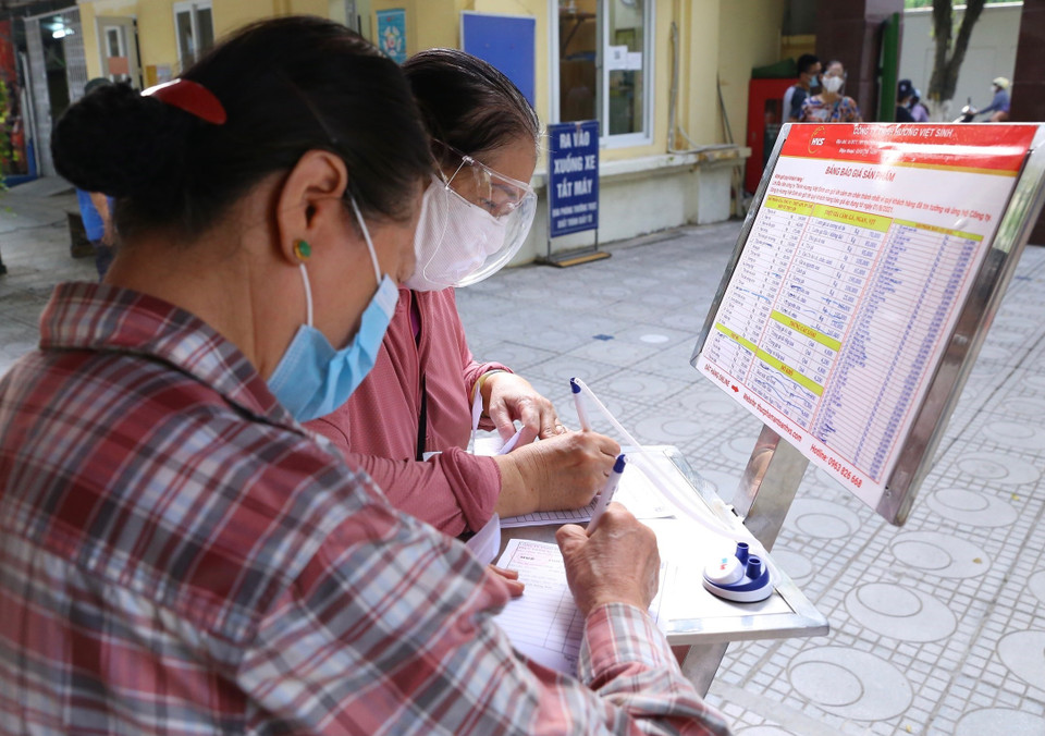 Người dân lựa chọn mặt hàng, số lượng và tự ghi lên phiếu mua. (Ảnh: Hoàng Hiếu/TTXVN)