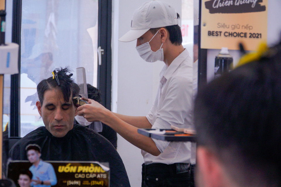 Nhân viên tại salon đều đeo khẩu trang, sát khuẩn tay khi cắt tóc cho khách. (Ảnh: Minh Hiếu/Vietnam+)