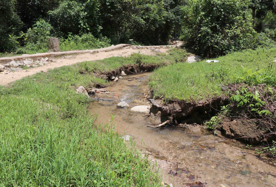 Con suối nhỏ nằm sâu trong di tích chạy dọc con đường tham quan bị biến dạng dòng chảy. (Ảnh: Xuân Tiến/TTXVN)