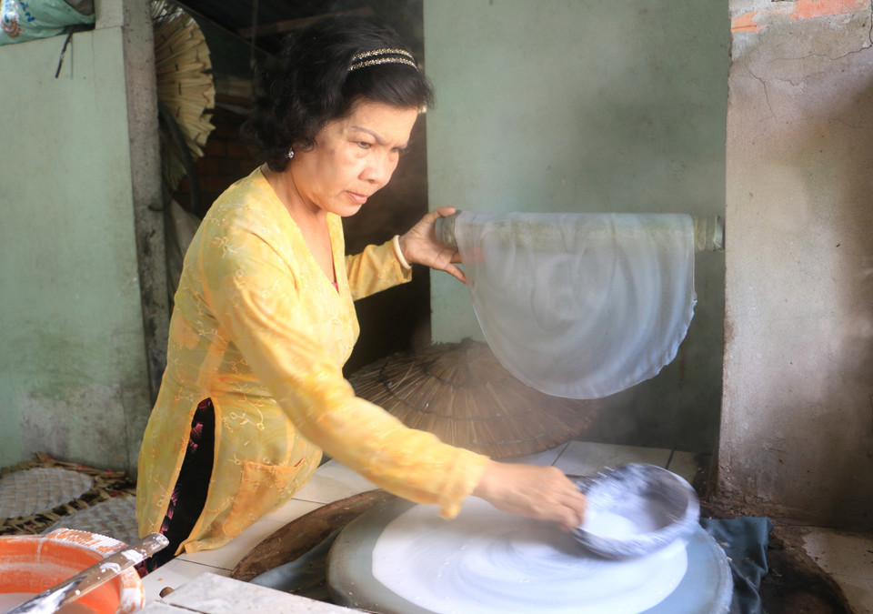 Bà Trần Thị Tuyết Mai, xã Lục Sĩ Thành, huyện Trà Ôn, tỉnh Vĩnh Long tỉ mỉ tráng từng chiếc bánh. (Ảnh: Lê Thúy Hằng/TTXVN)