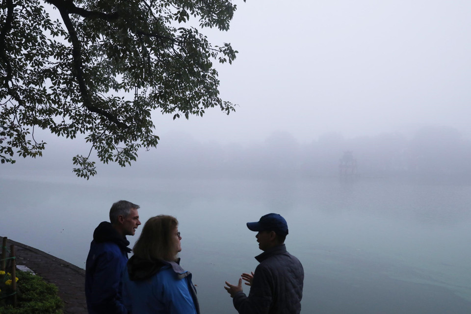 Một nhóm du khách quốc tế ngắm hồ Hoàn Kiếm trong sương sớm, ảnh chụp 8h ngày 6/2. (Ảnh: Lâm Khánh/TTXVN)