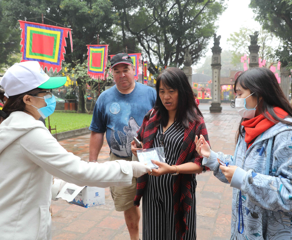 Phát khẩu trang miễn phí cho khách tham quan Di tích Quốc gia đặc biệt Văn Miếu-Quốc Tử Giám để phòng tránh dịch bệnh. (Ảnh: Thanh Tùng/TTXVN
