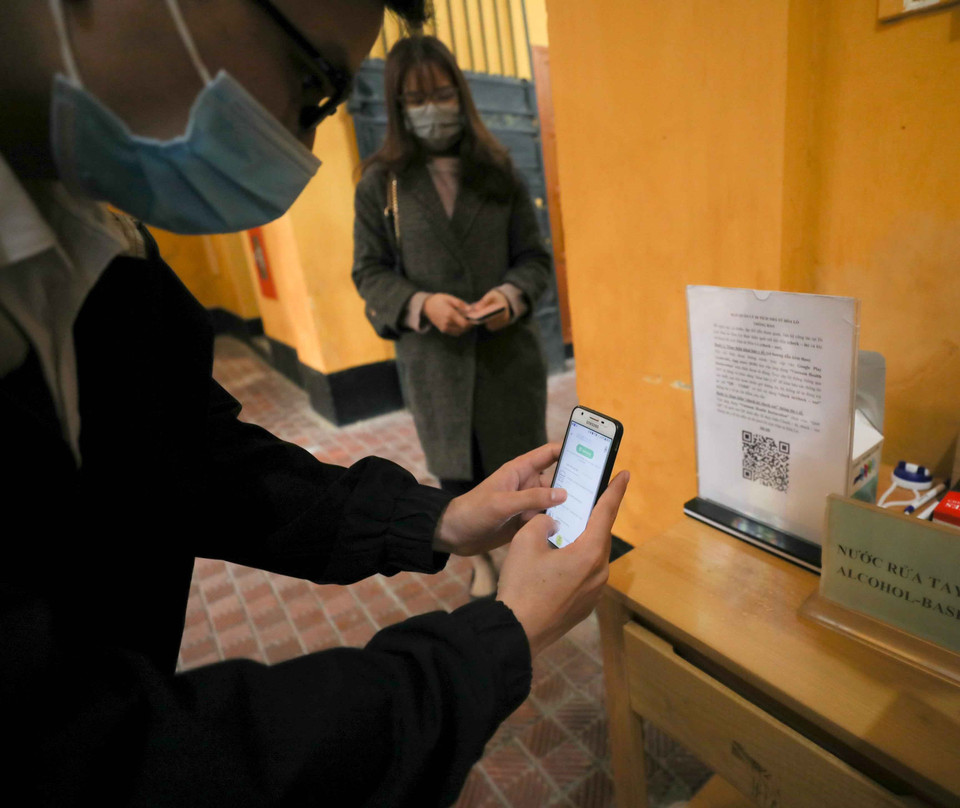 Khách tham quan di tích Nhà tù Hỏa Lò thực hiện quét mã QR code để khai báo y tế. (Ảnh: Thanh Tùng/TTXVN)