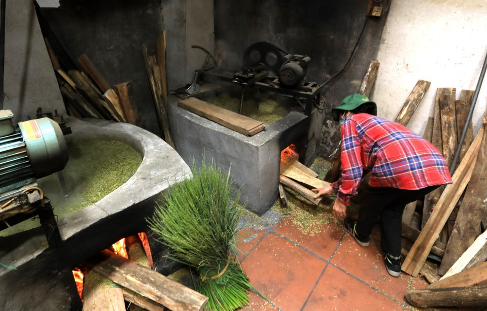 Khi tuốt xong, những hạt lúa được cho lên chảo rang to lửa, đảo đều bằng tay để lúa không cháy, đến độ hạt thóc bắt nhiệt chuyển dạng đông sữa quằn lại là được. Có máy gắn động cơ để đảo cốm nhưng người trông bếp vẫn thường xuyên phải để ý đến bếp lò và điều chỉnh nhiệt độ bếp sao cho lửa đều và không được để nhiệt độ quá cao khi mẻ rang sắp được. (Ảnh: Thành Đạt/TTXVN)