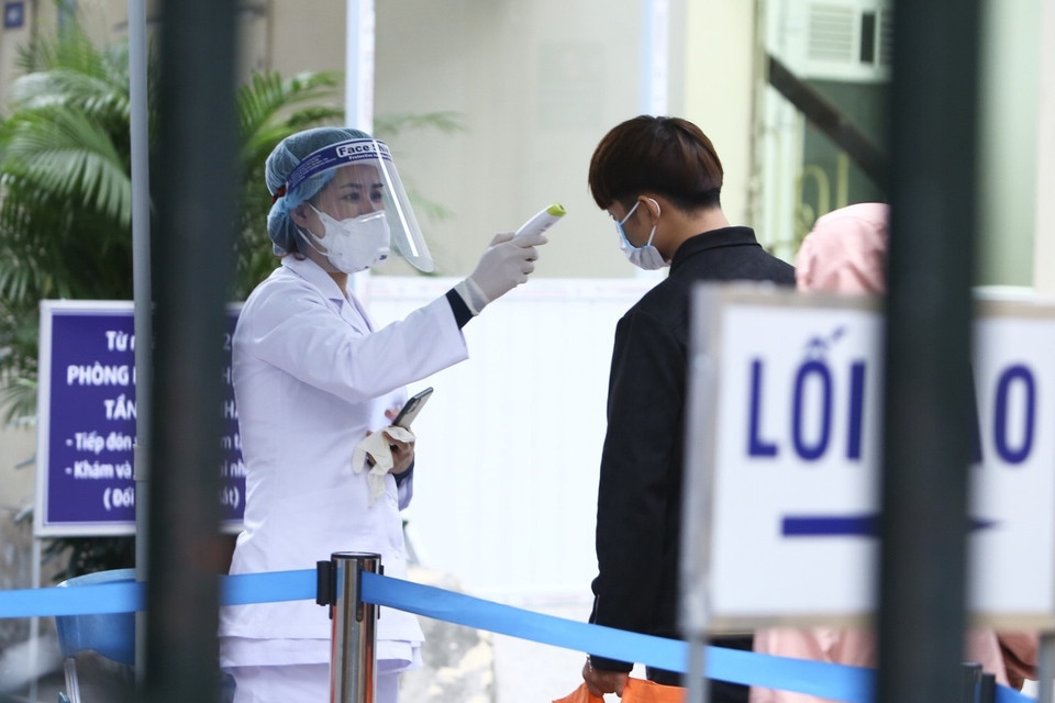 Người vào bệnh viện được kiểm tra thân nhiệt và khai báo lịch trình di chuyển. (Ảnh: Minh Quyết/TTXVN)