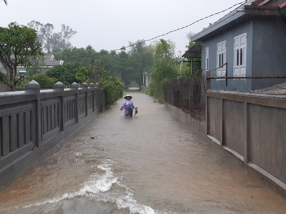 Người dân lội nước lụt tại thôn Xuân Tùy (xã Quảng Phú, huyện Quảng Điền). (Ảnh: Mai Trang/TTXVN)