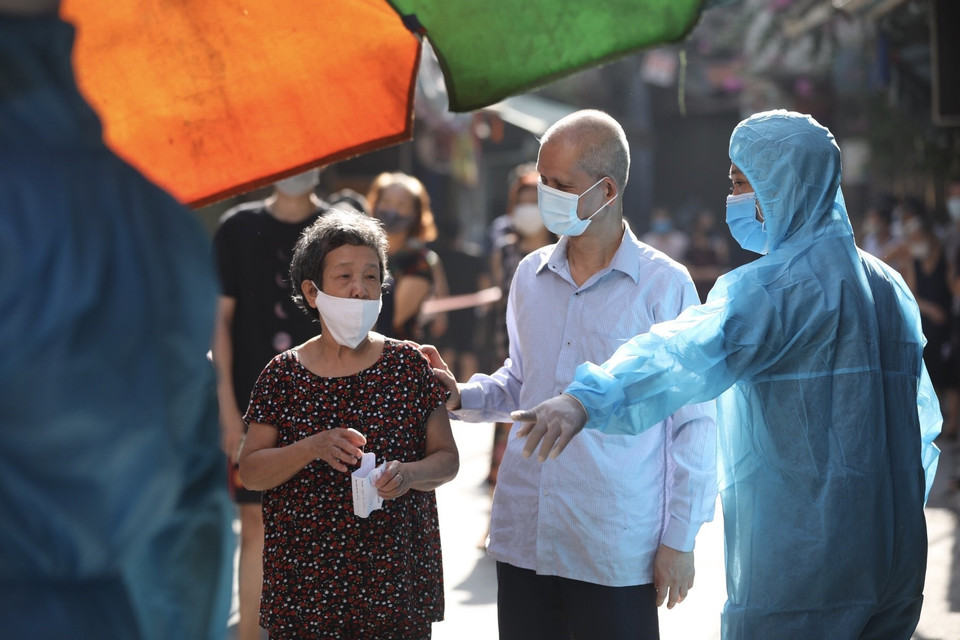 Nhân viên y tế hướng dẫn người dân ngõ 459 Bạch Mai, quận Hai Bà Trưng lấy mẫu xét nghiệm COVID-19. (Ảnh: Minh Quyết/TTXVN)