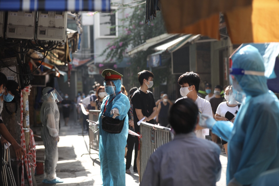 Lực lượng chức năng hướng dẫn người dân phường Bạch Mai, quận Hai Bà Trưng đến lấy mẫu xét nghiệm COVID-19. (Ảnh: Minh Quyết/TTXVN)