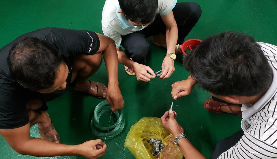 Tháo cuộn cước, gắn các thỏi chì, buộc lưỡi câu chuẩn bị cho một buổi câu đêm.(Ảnh: Hoàng Hùng/TTXVN)