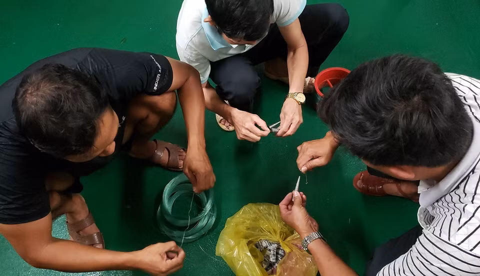 Tháo cuộn cước, gắn các thỏi chì, buộc lưỡi câu chuẩn bị cho một buổi câu đêm.(Ảnh: Hoàng Hùng/TTXVN)