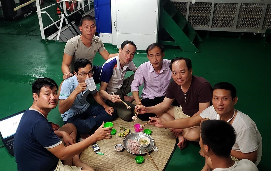 Hào hứng thưởng thức món gỏi cá ngay trên boong tàu. (Ảnh: Hoàng Hùng/TTXVN)