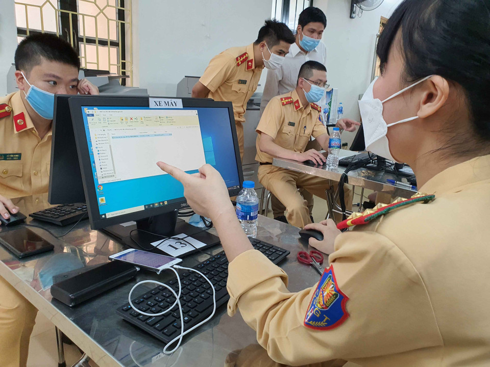 Cán bộ, chiến sỹ CSGT gấp rút hoàn thành thủ tục cấp giấy đi đường cho người dân. (Ảnh: Phạm Kiên/TTXVN)