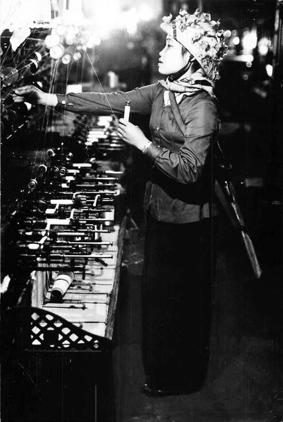 Trong các cuộc kháng chiến thống nhất đất nước, phụ nữ phát huy vai trò tham gia lao động sản xuất, là hậu phương vững chắc cho tiền tuyến cũng như trong sự nghiệp xây dựng chủ nghĩa xã hội ở miền Bắc. Trong ảnh: Nữ công nhân trong Nhà máy dệt tại TP Nam Định vừa làm việc, vừa đeo súng trường để sẵn sàng chiến đấu. (Ảnh: Tư liệu/TTXVN phát)