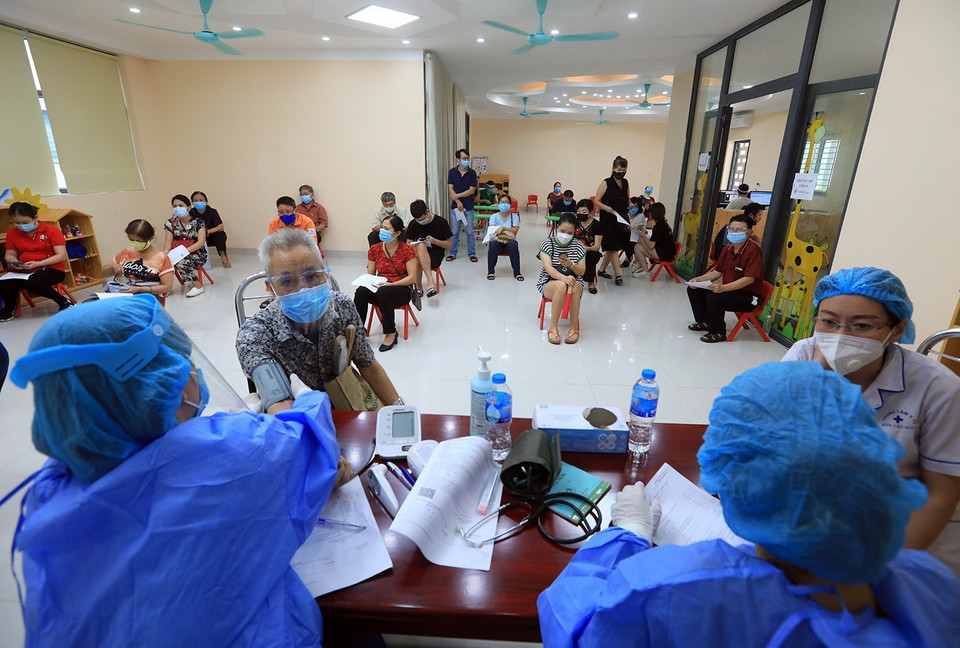 Nhân viên y tế đo huyết áp và kiểm tra thân nhiệt những người thuộc nhóm đối tượng được ưu tiên, người trên 65 tuổi và người mắc các bệnh nền mãn tính trước khi tiêm vaccine. (Ảnh: Tuấn Anh/TTXVN)