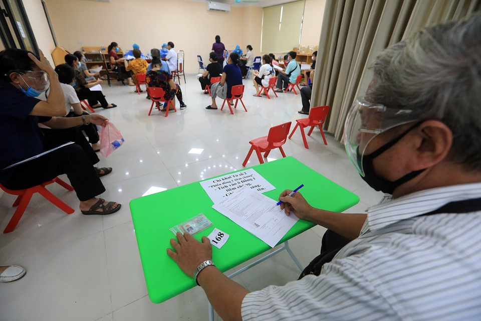 Người dân điền thông tin cá nhân trước khi được khám sàng lọc. (Ảnh: Tuấn Anh/TTXVN)