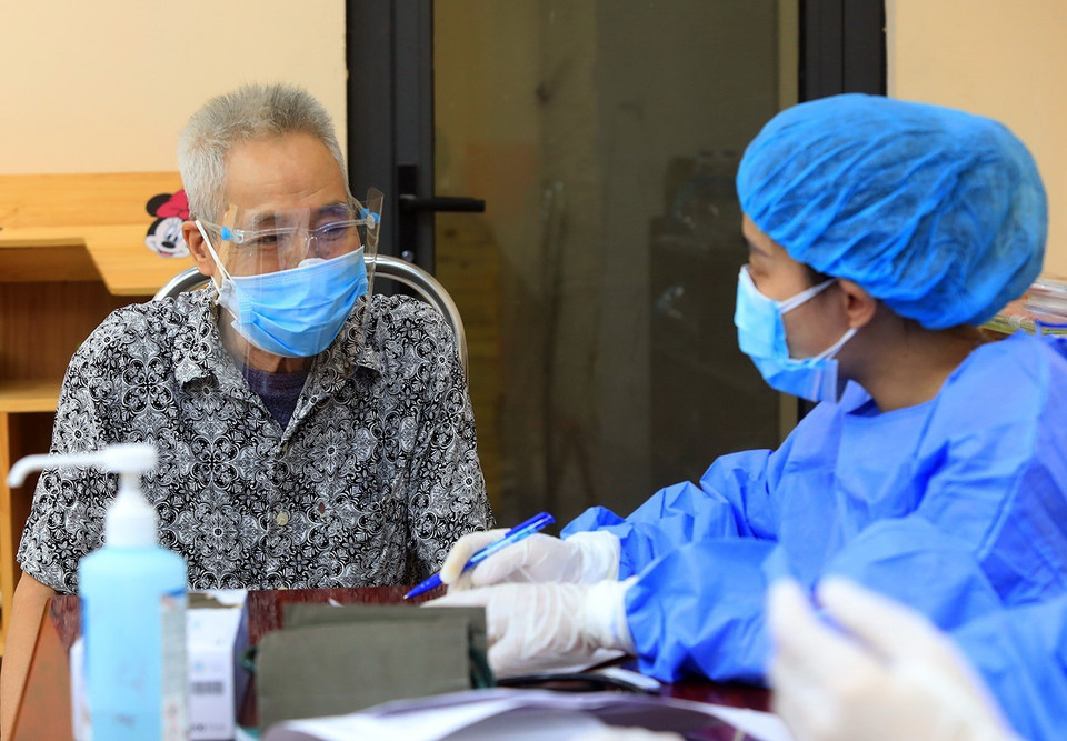 Ông Trịnh Xuân Nghĩa (77 tuổi), phường Trung Hòa, quận Cầu Giấy được nhân viên y tế tư vấn trước khi tiêm vaccine phòng COVID-19. (Ảnh: Tuấn Anh/TTXVN)