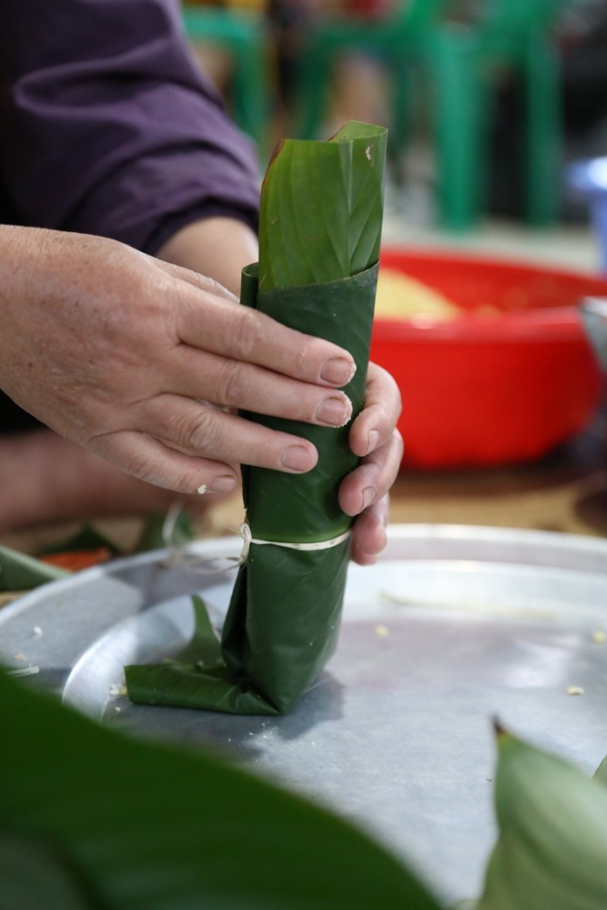 Gói bánh ống đòi hỏi sự khéo léo, cẩn thận để đảm bảo bánh bảo quản được lâu, dền và đẹp mắt. Nếu không khéo, bánh rất dễ một đầu to, một đầu nhỏ và lỏng lẻo. (Ảnh: Trọng Đạt/TTXVN)